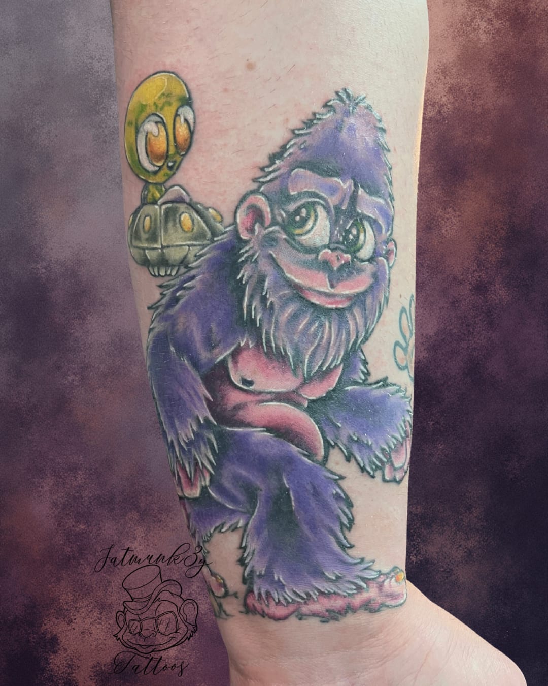 Custom color whimsical cartoon Bigfoot and alien tattoo on arm by Spencer Holmes, Fatmunk3y Tattoos Columbus Ohio