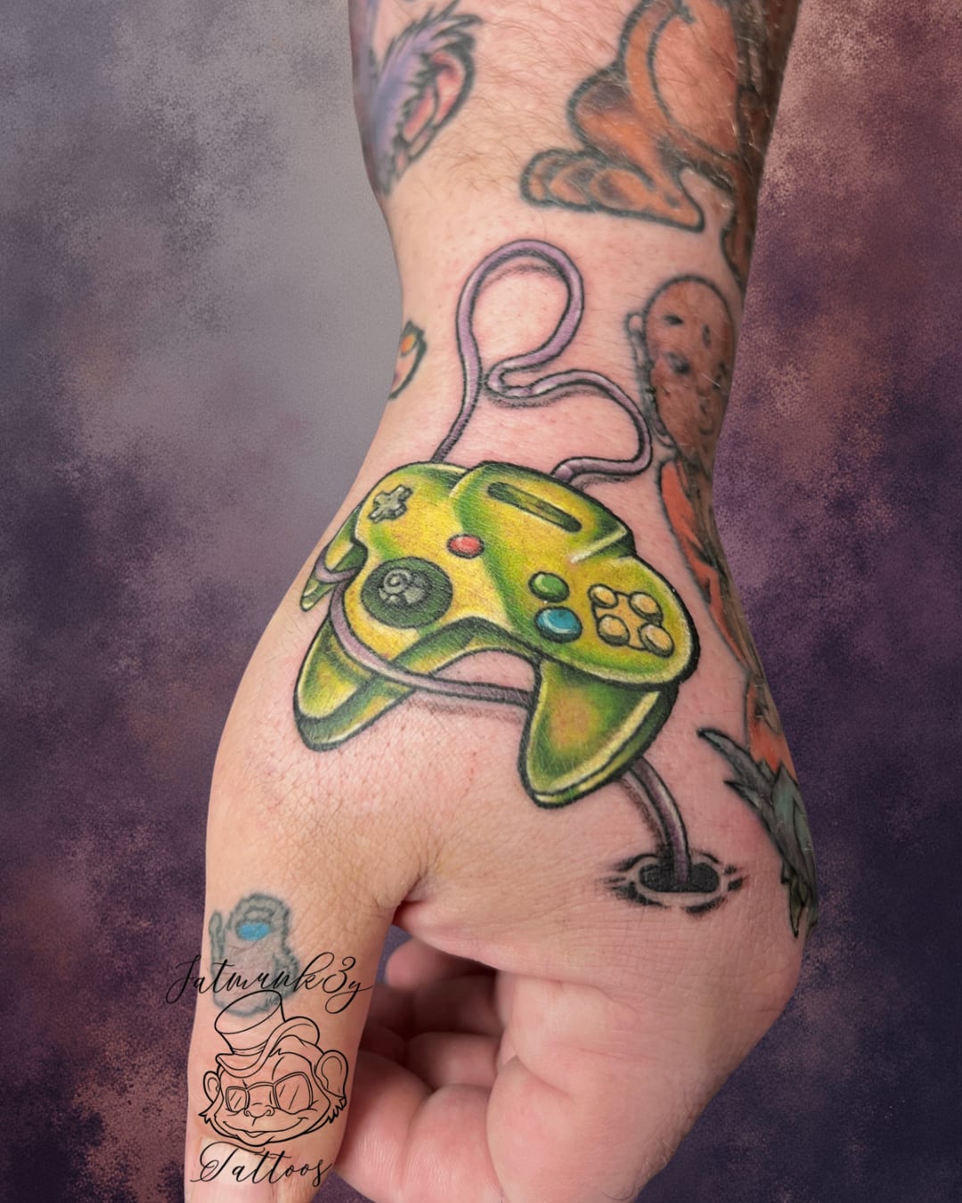 Custom color Nintendo 64 controller tattoo on hand by Spencer Holmes, Fatmunk3y Tattoos Columbus Ohio